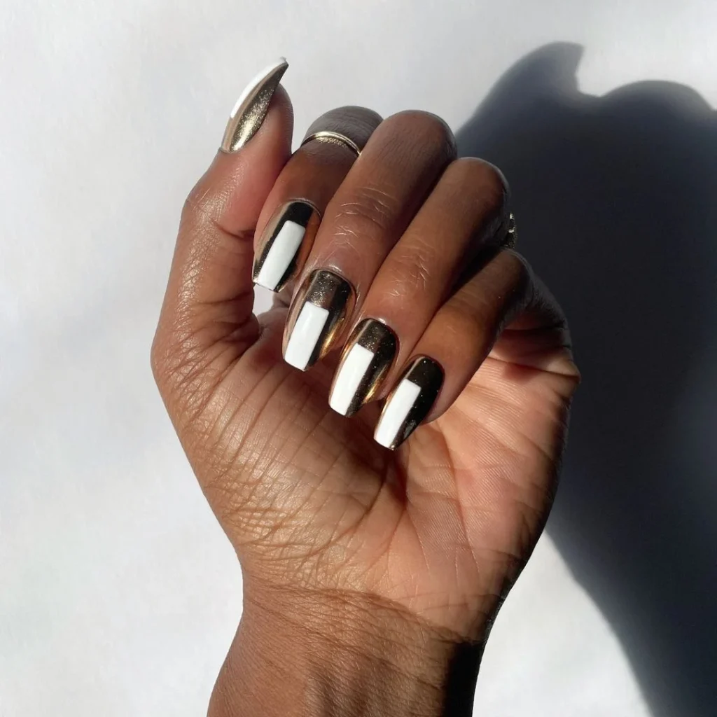 Acrylic Nail Designs for Every Skin Tone: Light, Medium, Tan & Dark 17 Metallic gold chrome acrylic nails on dark skin, glowing under warm light.