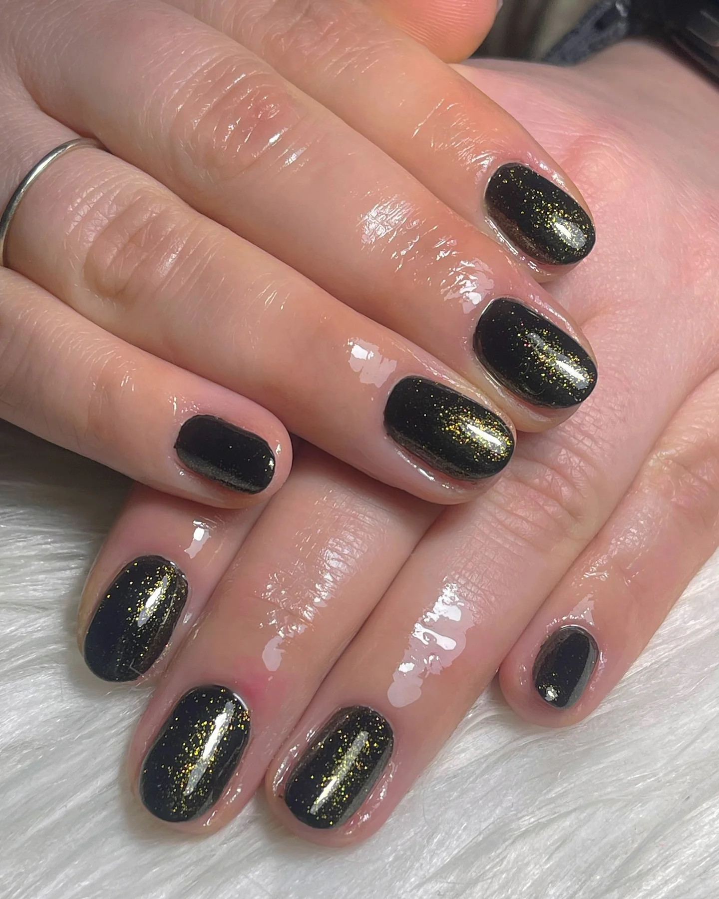 Glittery short black nails with a golden sheen