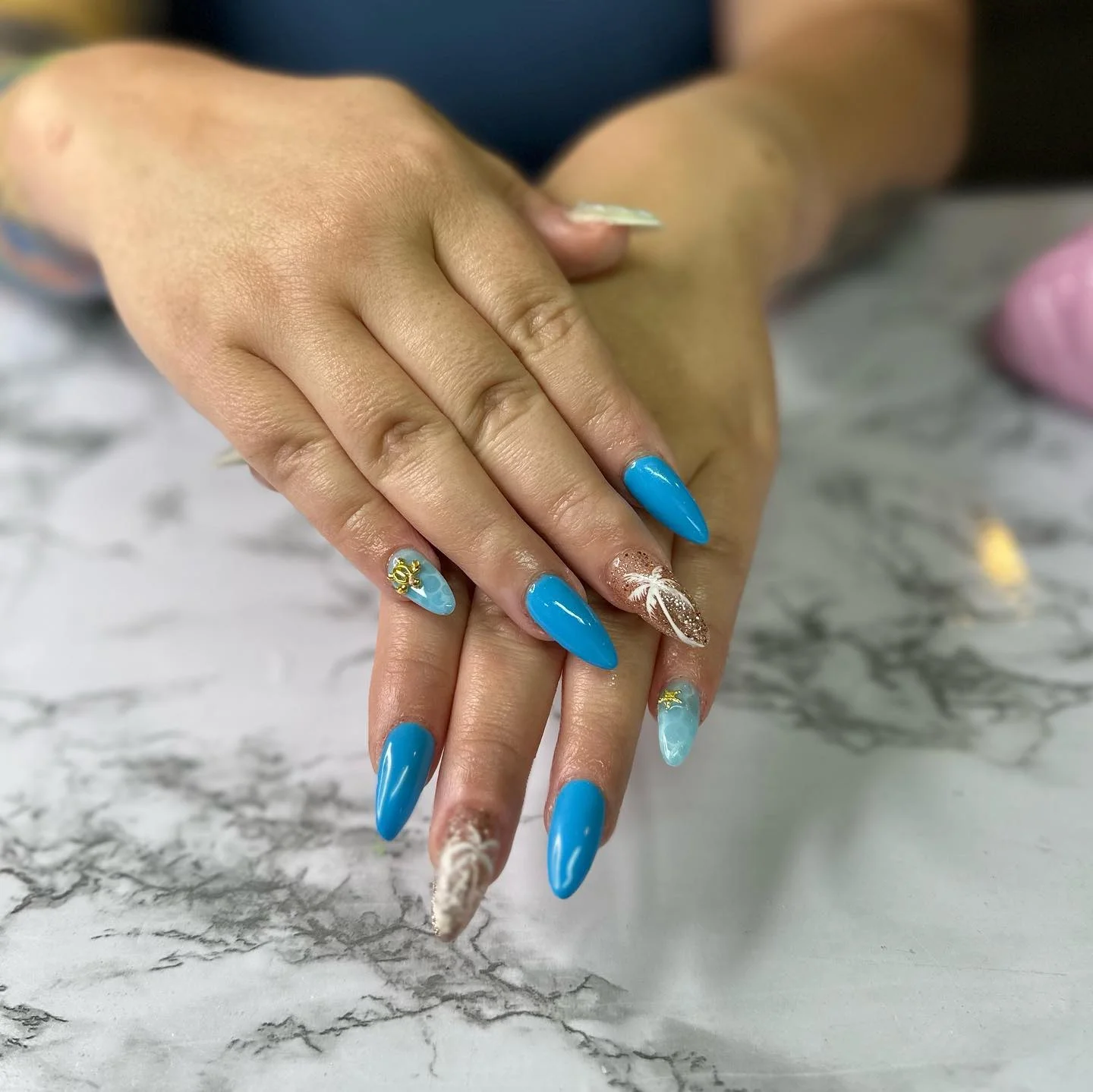 31 Nail Charm Ideas That Will Instantly Upgrade Your Nails in 2025 9 Blue almond nails with gold shell nail charm and beach accent