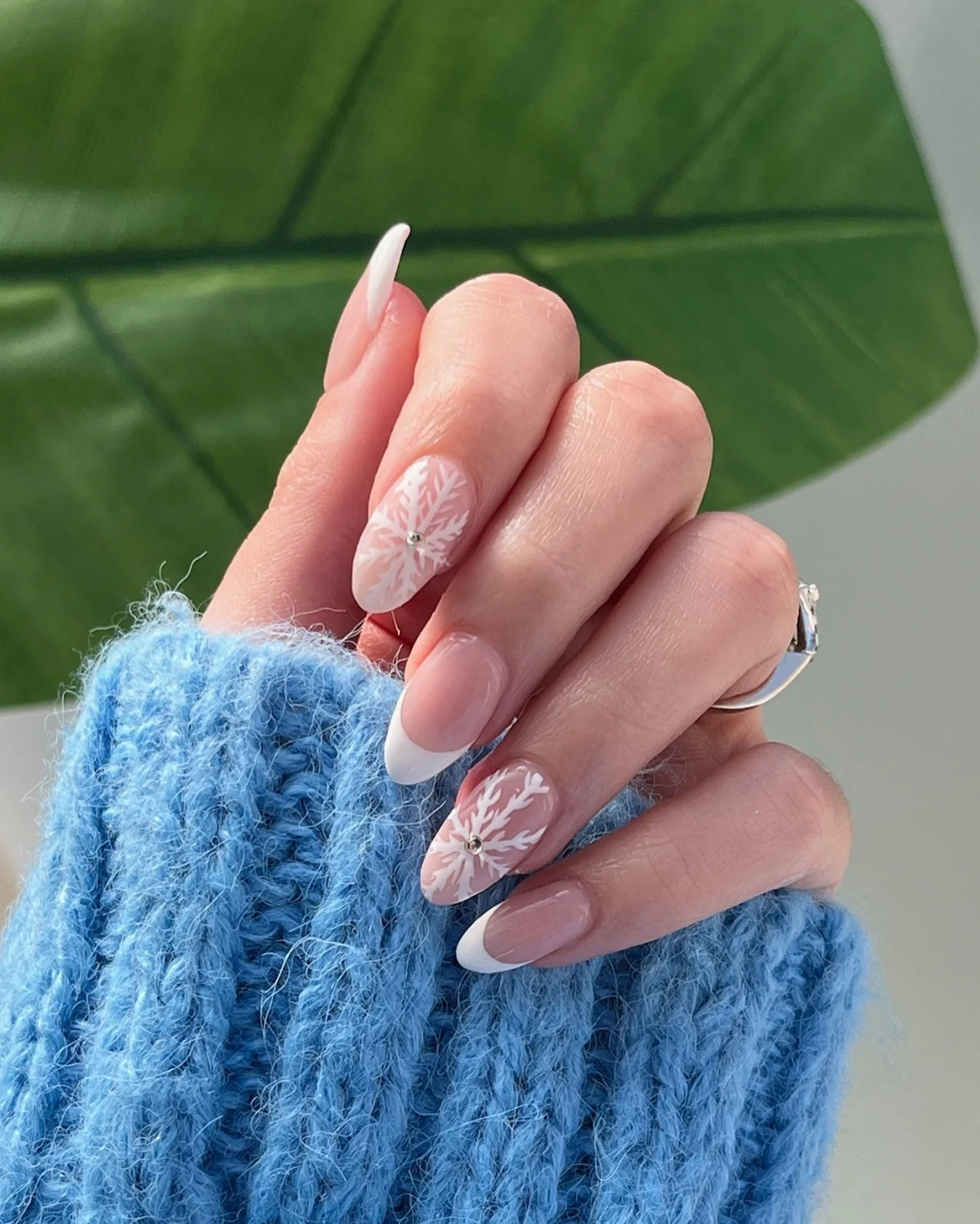 31 Nail Charm Ideas That Will Instantly Upgrade Your Nails in 2025 29 French almond nails with white snowflake charms and tiny crystal accent