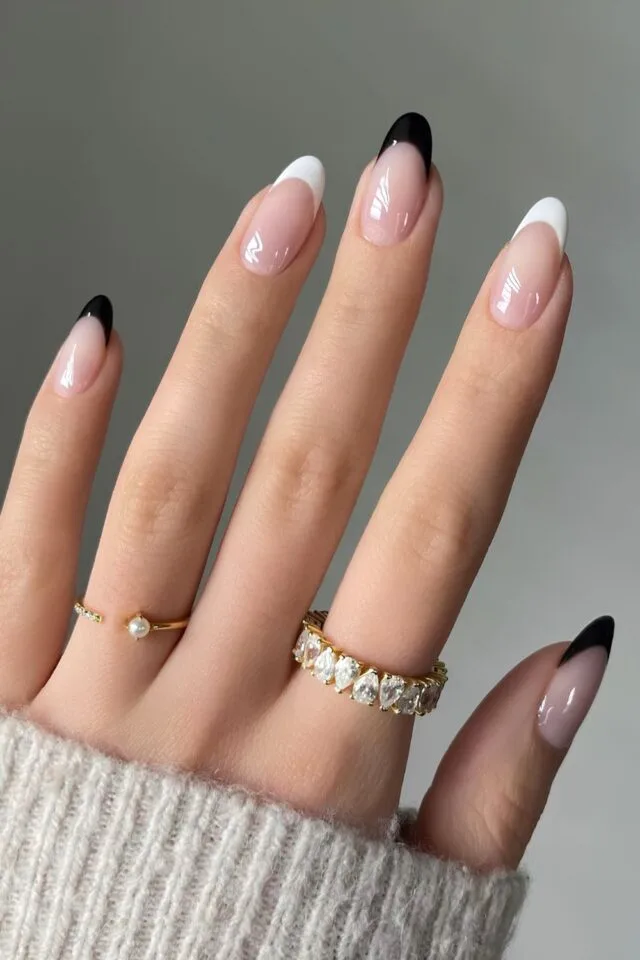 Black and White Nail Designs 2025: Chic Ideas for Every Occasion 10 Elegant almond-shaped French tip nails with alternating black and white tips on a nude base, creating a chic and modern manicure style.