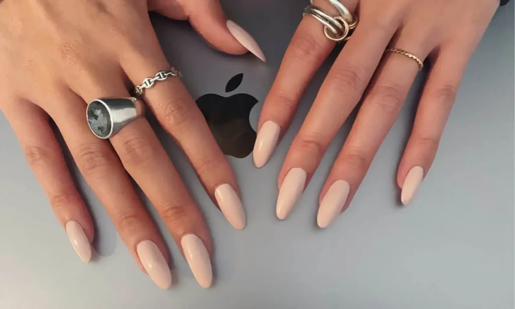 Matte beige almond nails styled with silver and gold rings, chic minimalist manicure idea 2025
