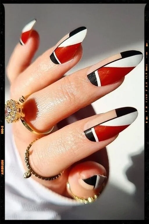 Black and White Nail Designs 2025: Chic Ideas for Every Occasion 15 Geometric red, black, and white nail art with bold angular patterns on almond-shaped nails, featuring modern color blocking for a chic and edgy manicure look.