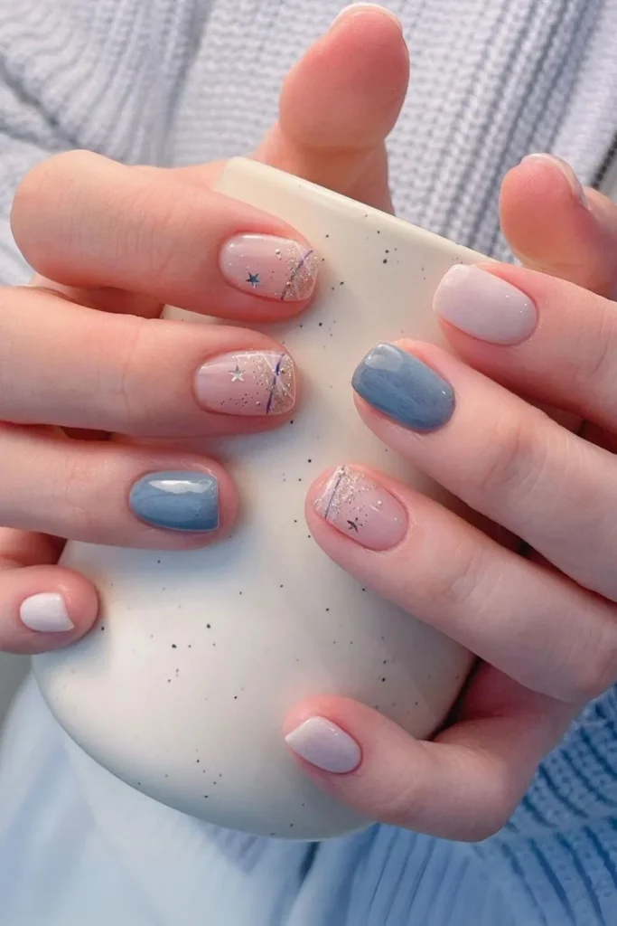 Skittle nails mixing navy blue, white, and a silver glitter accent with star and moon decals