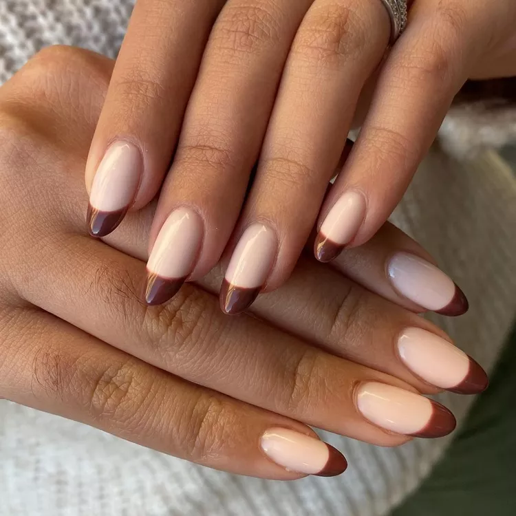 51 Easy Nail Designs You Can Do at Home (Even if You’re a Total Beginner) 52 Two hands showing long, oval nails with a modern French manicure featuring a clean, thick dark chocolate brown tip over a sheer milky pink base.