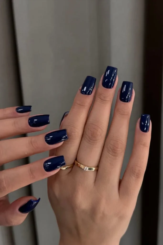 Short oval nails with deep, solid midnight blue glossy polish for an elegant and timeless look