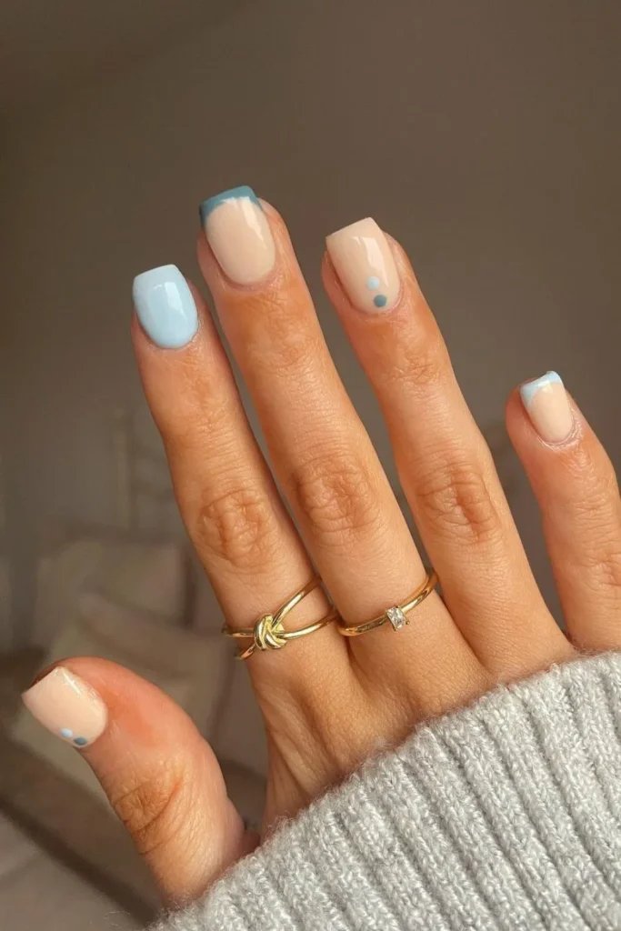 Minimalist short square nails with pastel blue tips and a simple beige base with a matching blue accent dot