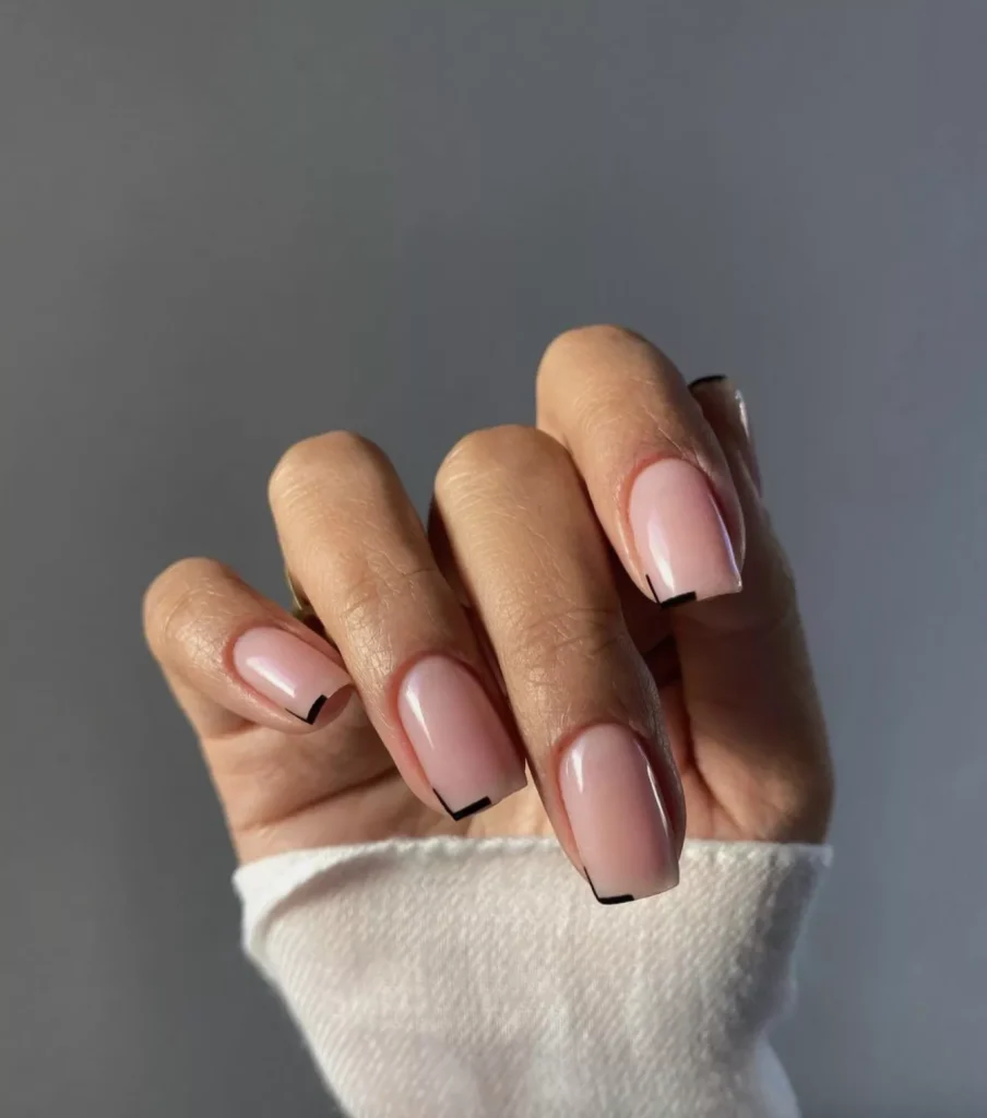 51 Easy Nail Designs You Can Do at Home (Even if You’re a Total Beginner) 43 Hand with medium-length square nails painted a milky sheer pink/nude color, featuring a thin, angular black outline on the side and tip, creating a subtle geometric border.