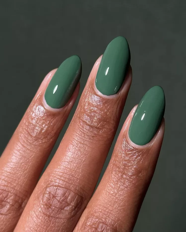 32+ Best Nail Colors for Dark Skin That Look Absolutely Stunning 11 Close-up of almond-shaped nails on deep brown skin, coated in a rich, opaque, and glossy hunter green polish. This deep forest green is a perfect jewel tone for the fall and winter seasons.