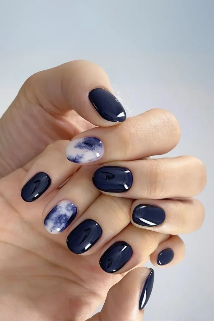 Navy blue marble nail art with gold foil accents and solid dark blue polish on short square nails