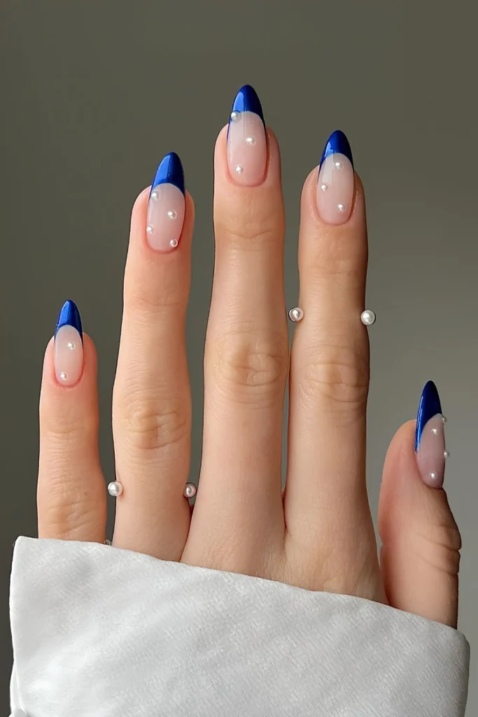 Deep sapphire blue French tips with white pearl shimmer over a sheer nude base