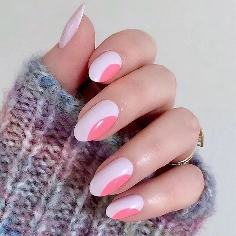 51 Easy Nail Designs You Can Do at Home (Even if You’re a Total Beginner) 29 Hand resting on a fuzzy pastel sweater, showcasing long, oval nails with a two-toned design featuring a soft, wavy line separating the white base from the bright pink lower section.
