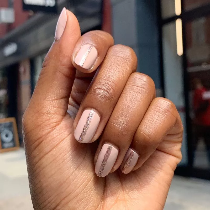 51 Easy Nail Designs You Can Do at Home (Even if You’re a Total Beginner) 30 Hand with short, square nails painted a pale nude/pink base color, accented by a single thick, vertical stripe of sparkly rose gold glitter down the center of each nail.