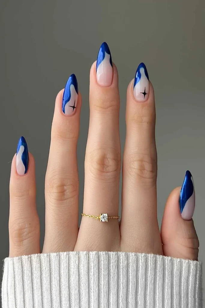 Long almond nails with an abstract blue swirl design and a delicate black star accent over a sheer nude base.