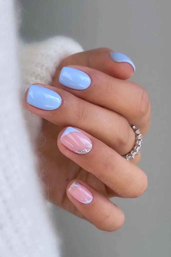 Short square nails with an alternating manicure of solid light blue and a sheer pink base with silver micro-glitter French tips.