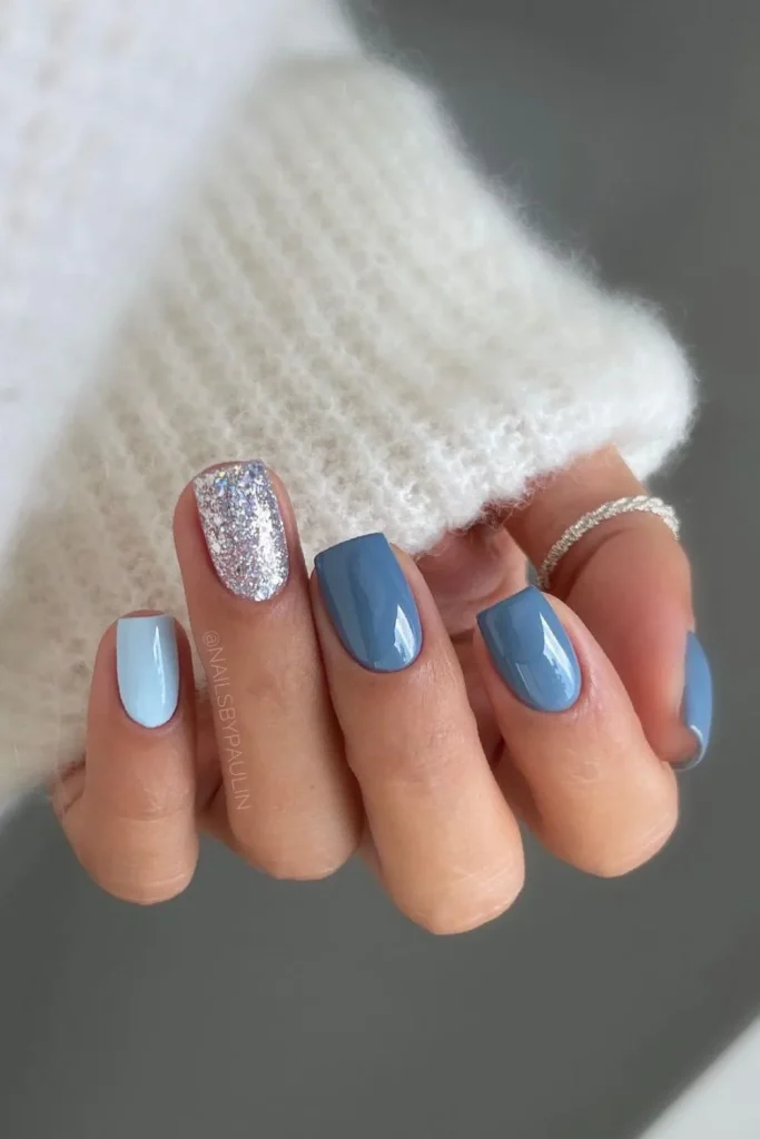 Matte slate blue nails with a subtle chrome shimmer accent on short, rounded square nails