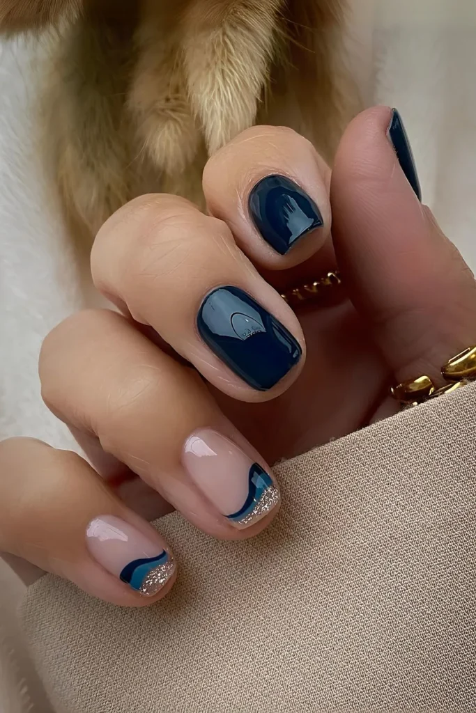 Short square nails with dark blue and glitter swirl French tips and a solid navy accent nail