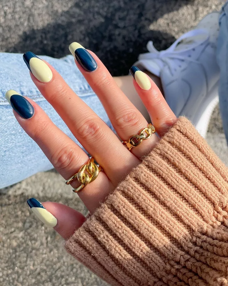 30 Stunning Dark Blue Nail Designs for a Denim-Inspired Summer Look 6 Deep navy and pastel yellow alternating French tips on almond nails. A trendy color-block spring manicure idea with gold ring accents.