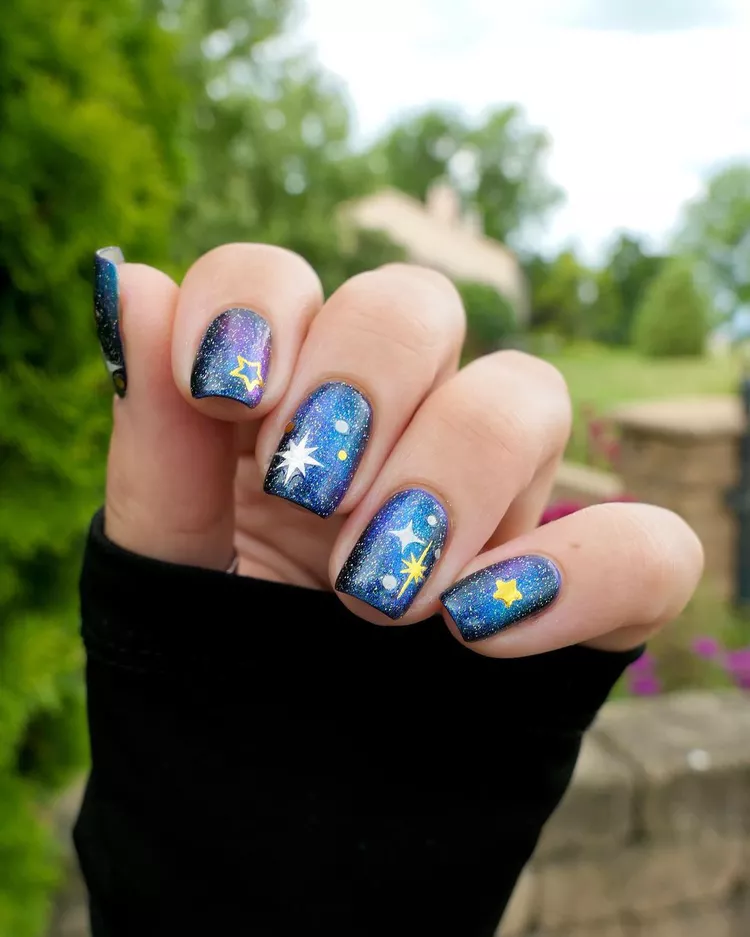 30 Stunning Dark Blue Nail Designs for a Denim-Inspired Summer Look 29 Stunning galaxy nail art with deep blue and purple cosmic glitter. Features hand-painted stars for a fun, creative celestial manicure design.