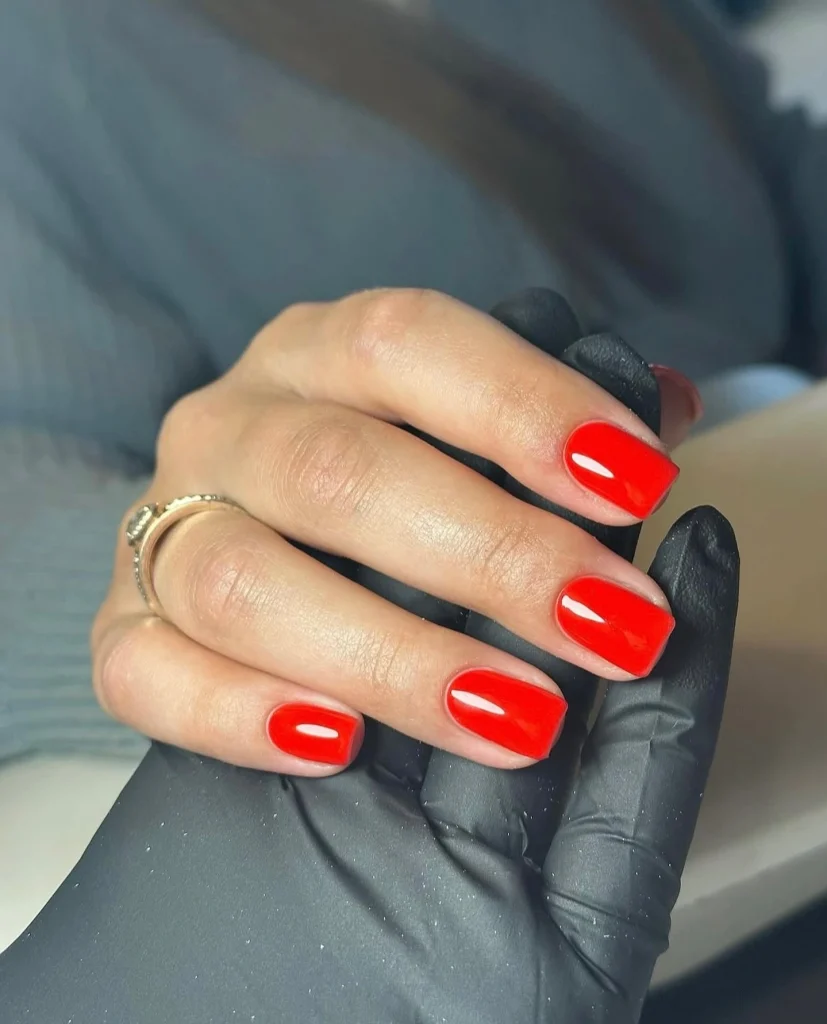 warm red nail colors for women over 50 — classic red manicure flattering mature hands